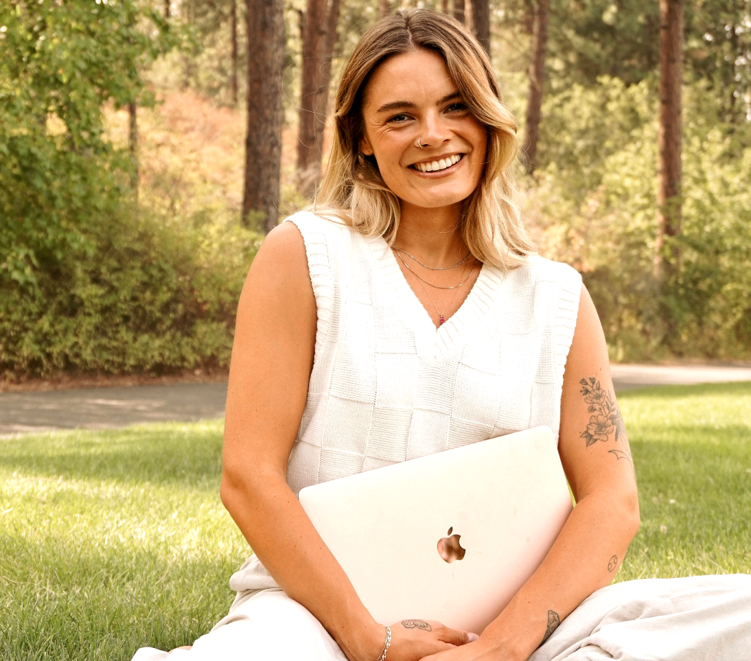 Girl sitting with her computer in the grass